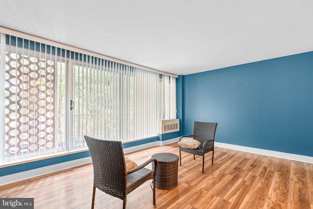 living area with an AC wall unit, plenty of natural light, baseboards, and wood finished floors