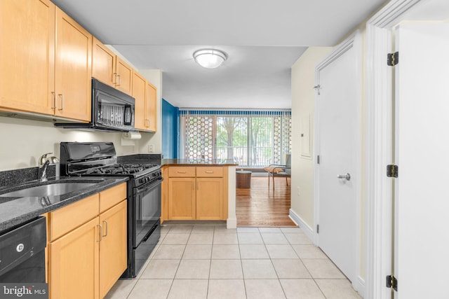 kitchen featuring light tile patterned floors, light brown cabinetry, a sink, a peninsula, and black appliances