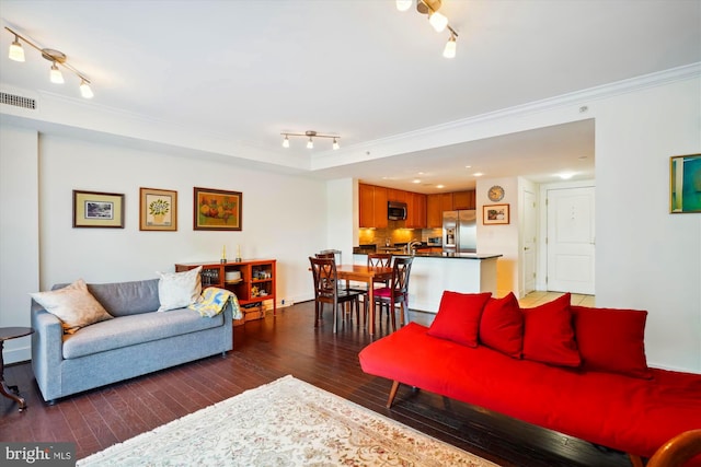 living room featuring dark hardwood / wood-style flooring, track lighting, and ornamental molding