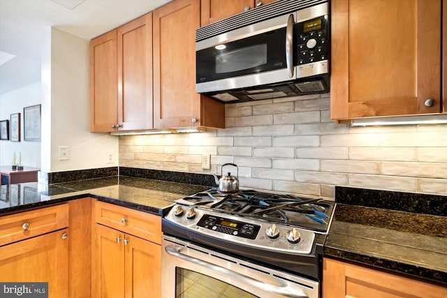 kitchen with dark stone counters, stainless steel appliances, tile patterned floors, and tasteful backsplash