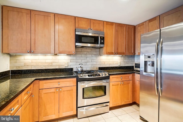 kitchen with dark stone counters, light tile patterned floors, backsplash, and stainless steel appliances