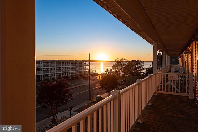 balcony at dusk featuring a water view