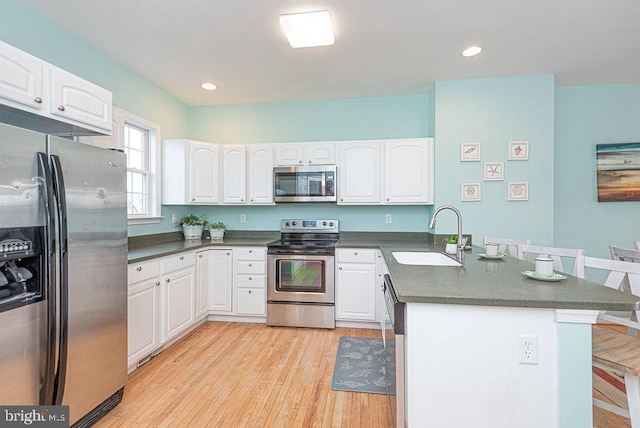 kitchen featuring appliances with stainless steel finishes, sink, light hardwood / wood-style floors, and white cabinets