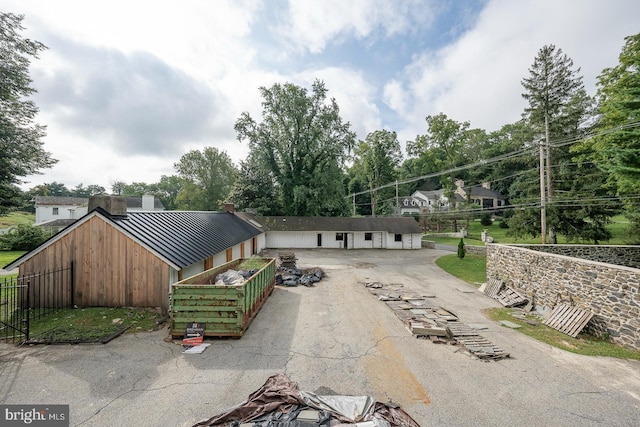 view of front of property with aphalt driveway, a standing seam roof, metal roof, and fence