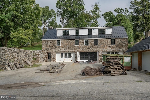 view of front of property with stone siding, a standing seam roof, metal roof, and a chimney