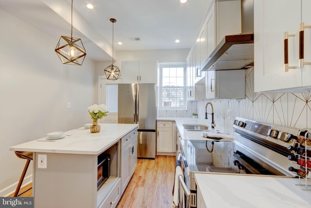 kitchen featuring stainless steel appliances, wall chimney range hood, a center island, sink, and white cabinetry