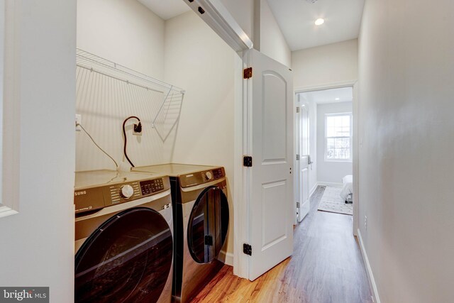 clothes washing area featuring light hardwood / wood-style floors and washer and clothes dryer