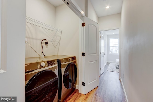 washroom with light hardwood / wood-style floors and washing machine and clothes dryer