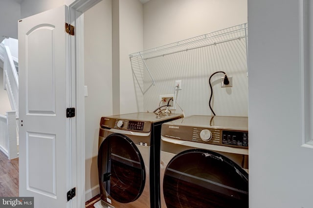 clothes washing area with hardwood / wood-style floors and washer and clothes dryer