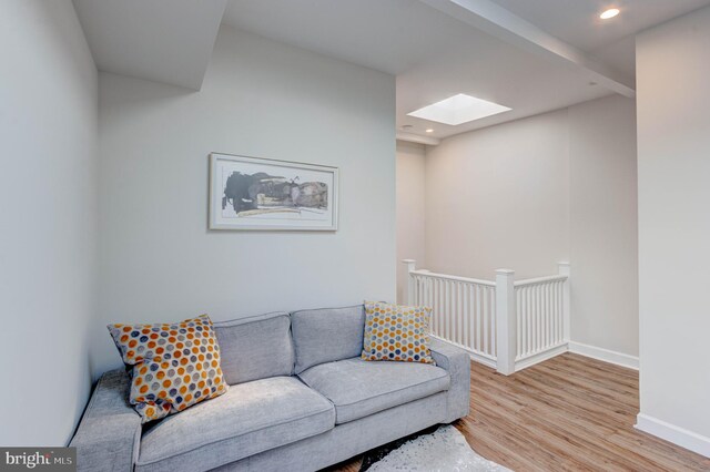 living room featuring light hardwood / wood-style floors and a skylight