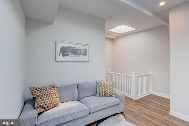 living room with light wood-type flooring and a skylight