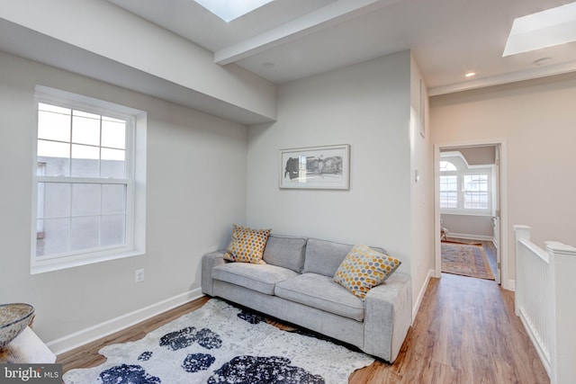 living room with light wood-type flooring and a skylight