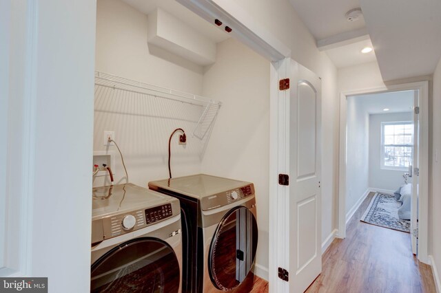 clothes washing area featuring light hardwood / wood-style floors and washing machine and dryer