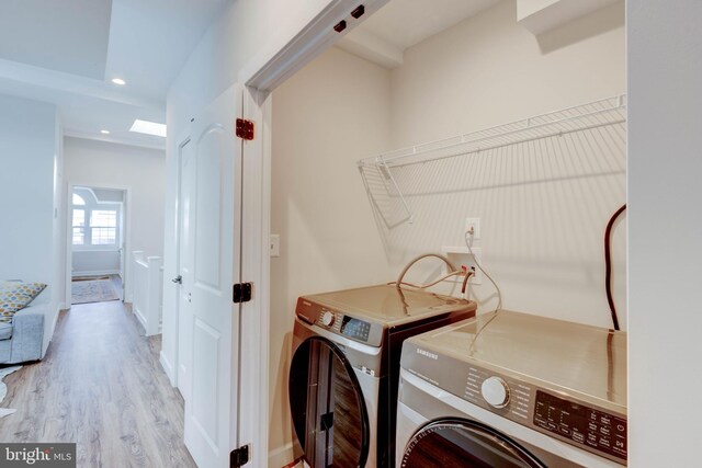 clothes washing area with light wood-type flooring and washer and clothes dryer