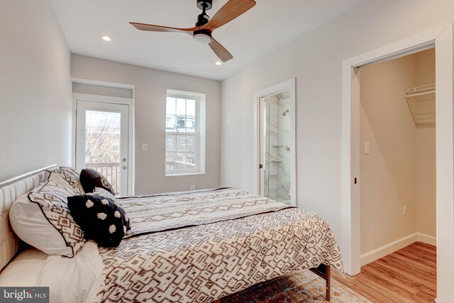 bedroom with light wood-type flooring, ceiling fan, a walk in closet, and ensuite bath