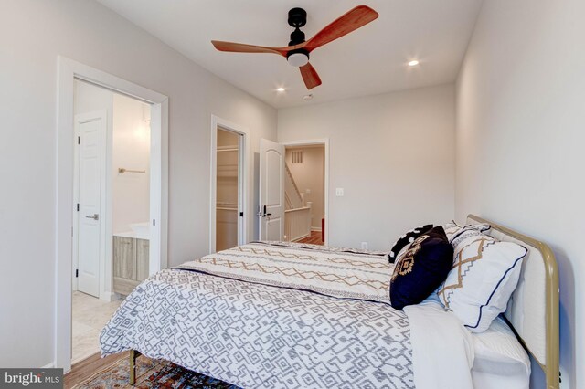 bedroom featuring ceiling fan, a spacious closet, light colored carpet, a closet, and ensuite bath