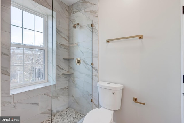 bathroom with a tile shower and toilet