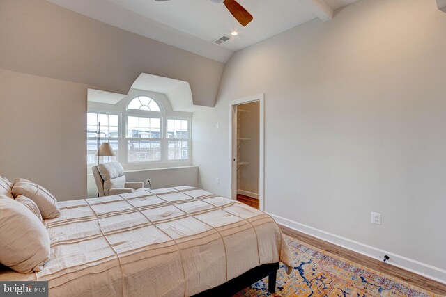 bedroom with a walk in closet, a closet, vaulted ceiling with beams, and wood-type flooring