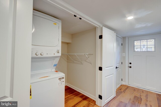 laundry area with light hardwood / wood-style floors and stacked washer / dryer