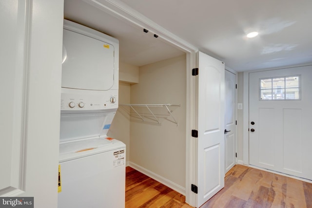 washroom with stacked washer and clothes dryer and light hardwood / wood-style flooring