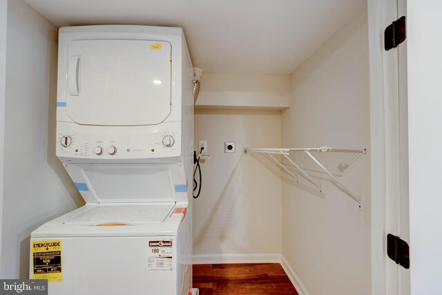 laundry room featuring stacked washing maching and dryer and hardwood / wood-style flooring