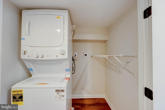 clothes washing area featuring stacked washing maching and dryer and hardwood / wood-style floors