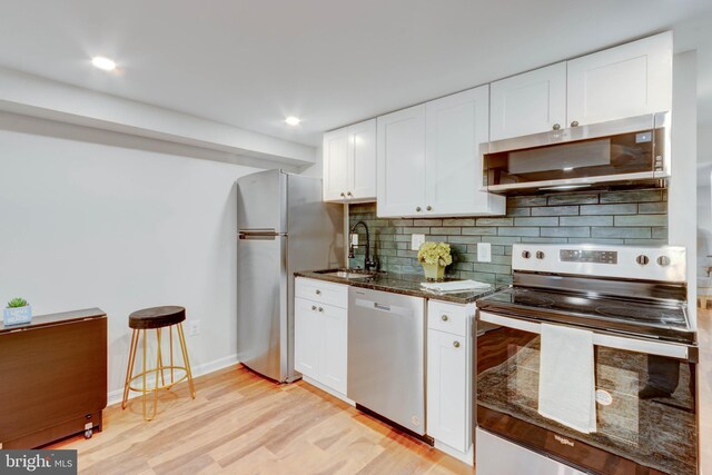 kitchen featuring stainless steel appliances, light hardwood / wood-style flooring, tasteful backsplash, sink, and white cabinets