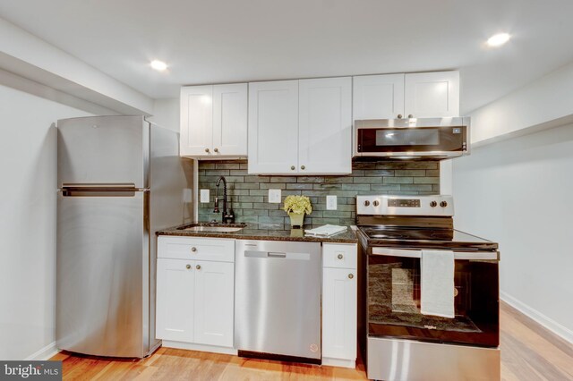 kitchen featuring white cabinetry, stainless steel appliances, light hardwood / wood-style flooring, and tasteful backsplash