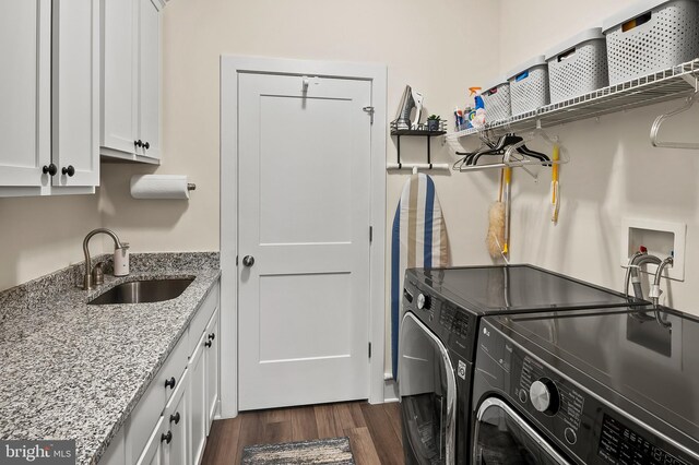 laundry room featuring dark wood-type flooring, cabinets, washer and clothes dryer, and sink