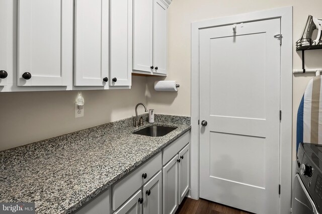 kitchen with white cabinetry, dark hardwood / wood-style flooring, light stone counters, and sink