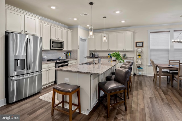 kitchen featuring a center island with sink, appliances with stainless steel finishes, a breakfast bar, dark wood-type flooring, and sink