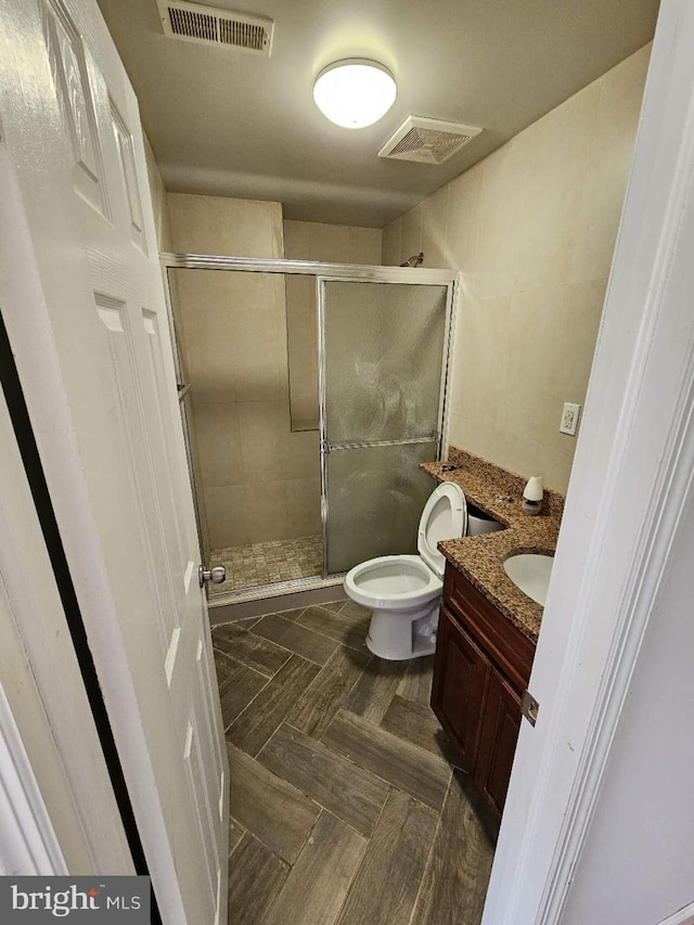 bathroom featuring parquet flooring, vanity, walk in shower, and toilet