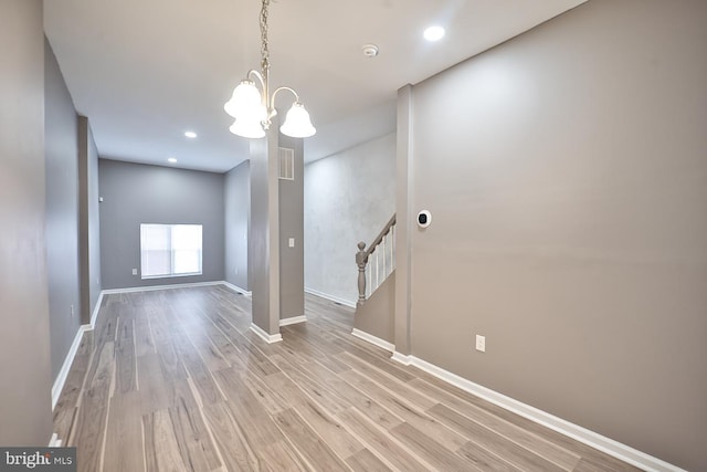 spare room featuring a chandelier and light hardwood / wood-style floors