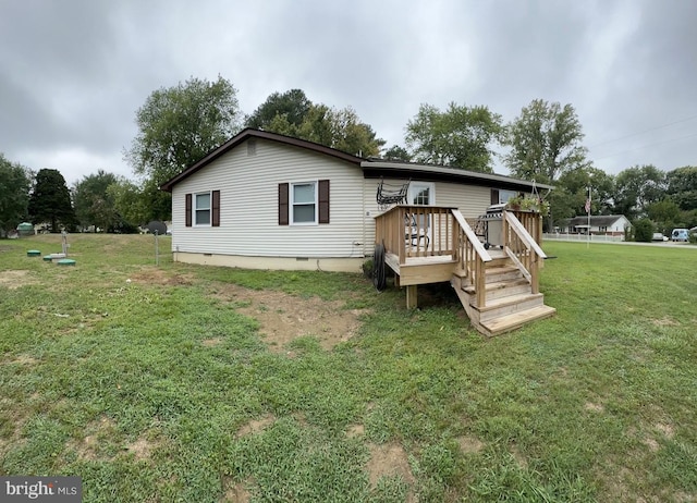 rear view of house with crawl space, a deck, and a yard