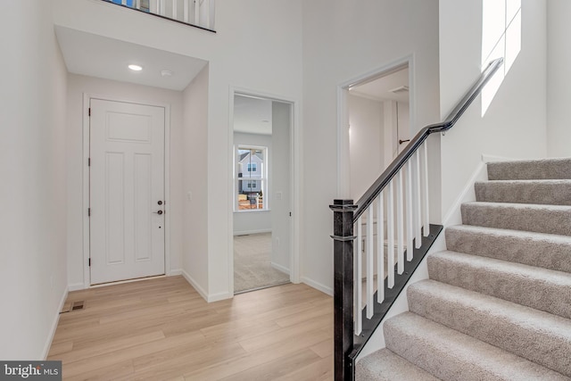 foyer featuring recessed lighting, a high ceiling, baseboards, stairs, and light wood-type flooring