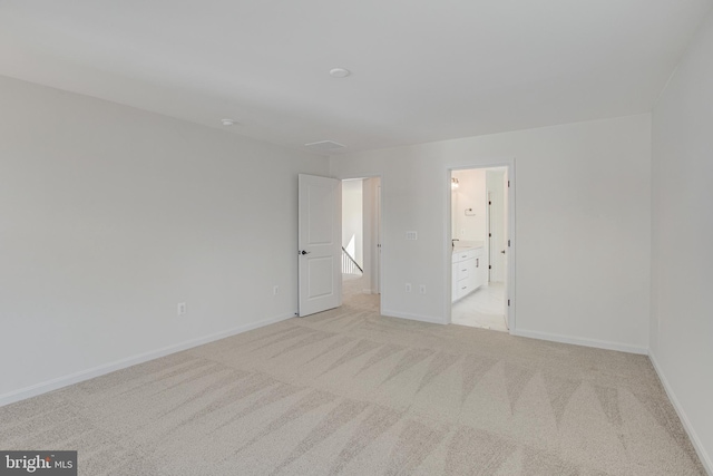 unfurnished bedroom featuring light colored carpet, connected bathroom, and baseboards