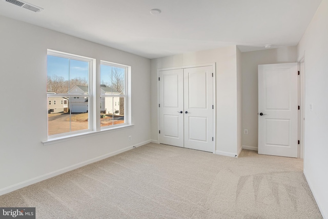 unfurnished bedroom featuring carpet floors, a closet, visible vents, and baseboards