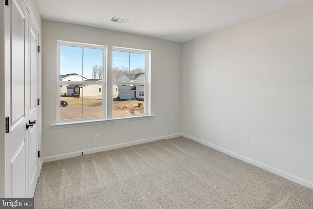 spare room featuring baseboards, visible vents, and carpet flooring