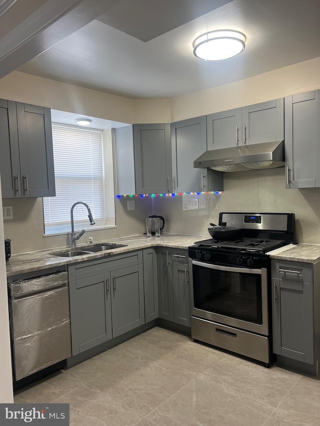 kitchen with appliances with stainless steel finishes, tasteful backsplash, sink, gray cabinetry, and light tile patterned floors