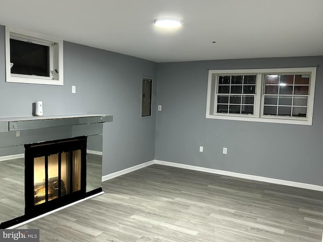 unfurnished living room featuring electric panel, a fireplace, and wood-type flooring