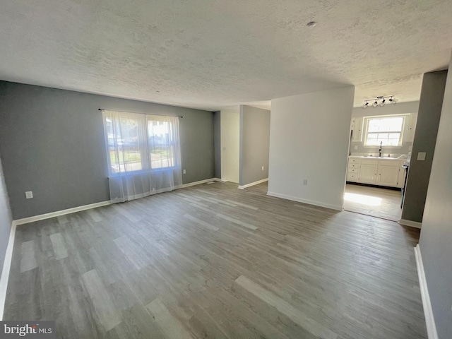 spare room with sink, light wood-type flooring, and a textured ceiling