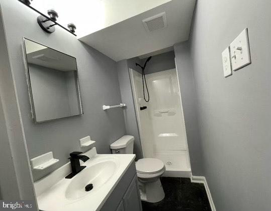 bathroom with vanity, a shower, and toilet