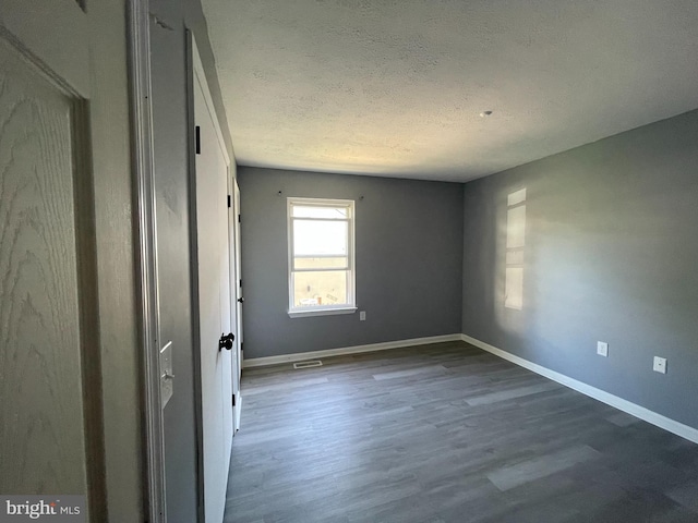 unfurnished room featuring hardwood / wood-style flooring and a textured ceiling