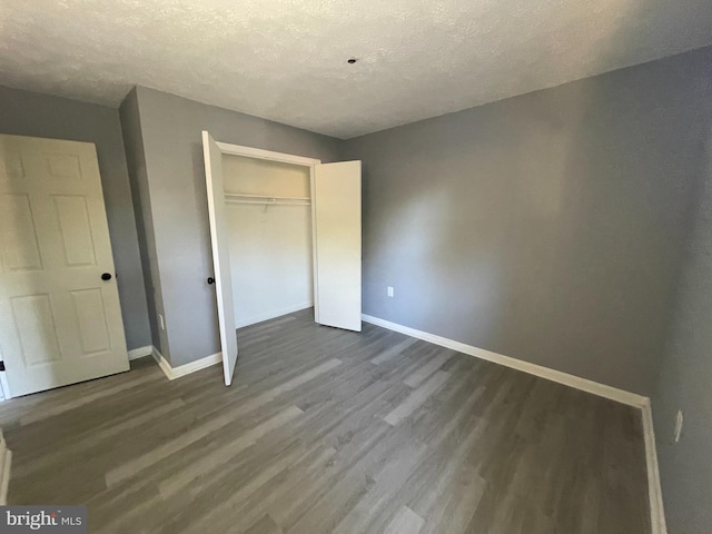 unfurnished bedroom with dark wood-type flooring, a closet, and a textured ceiling