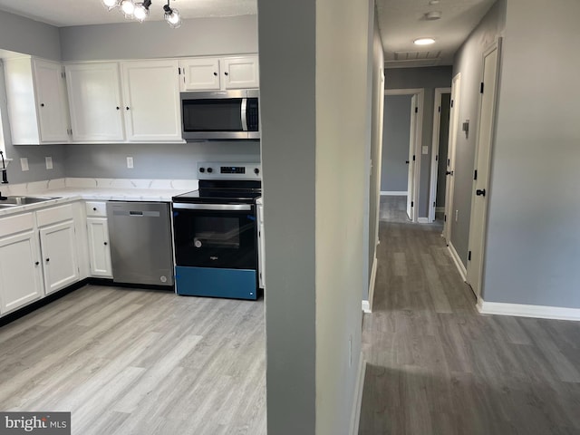 kitchen with stainless steel appliances, light wood-type flooring, sink, and white cabinetry