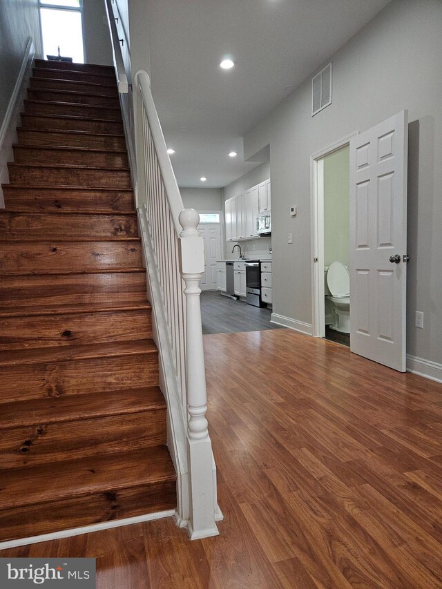 kitchen with dark wood-type flooring, sink, appliances with stainless steel finishes, and white cabinetry