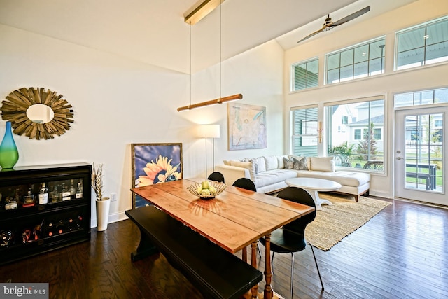 dining area featuring dark wood-type flooring and a towering ceiling