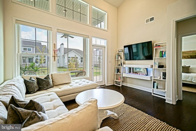 living room with plenty of natural light, a towering ceiling, and hardwood / wood-style flooring