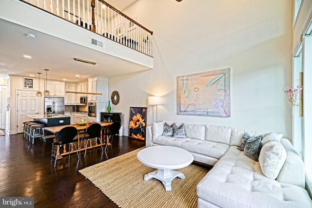 living room with a towering ceiling and dark hardwood / wood-style floors