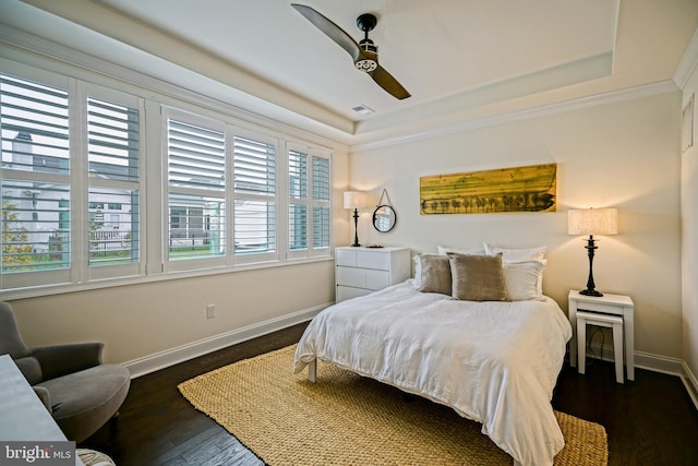 bedroom featuring a tray ceiling, dark wood-type flooring, crown molding, and ceiling fan